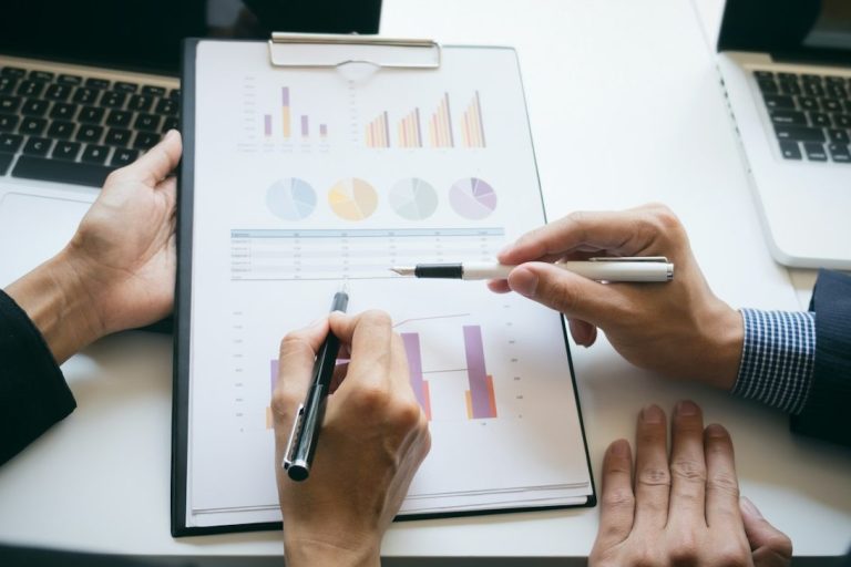 Hände halten einen Clipboard mit Diagrammen und Analyseergebnissen.